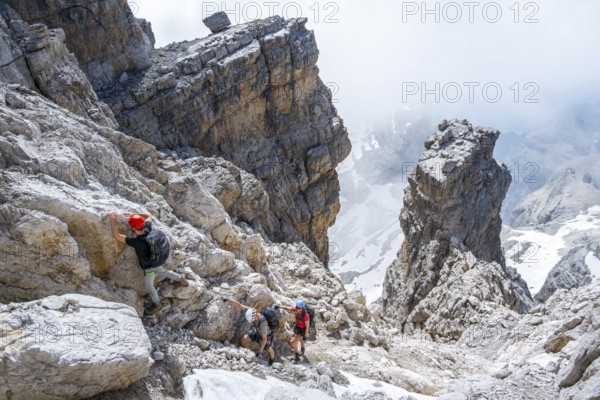 Three hikers climb the Cima falconer mountain peak, Brenta Mountains, Brenta, Brenta-Adamello Natural Park, Trentino, Italy
