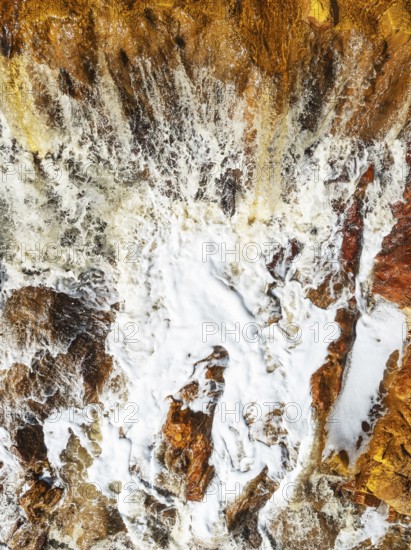 Detail of a waterfall in the Rio Tinto (Red river) with its orange-red hue due to oxidised iron minerals. Aerial view. Drone shot. Huelva province, Andalusia, Spain
