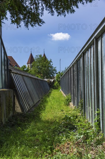 Greenhouses bear witness to the tradition of vegetable growing in the Niederzell district on the island of Reichenau, Lake Constance, Baden-Württemberg, Germany, with the church of St Peter and St Paul in the background