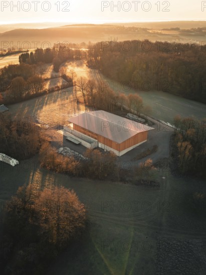 A building surrounded by trees in the warm light of an autumn sunset seen from the air, Gechingen, Heckengäu region, district of Calw, Germany
