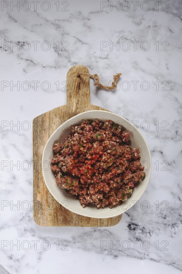 Raw minced meat, marinated with spices and herbs, in a bowl, minced meat with spices, top view, homemade, no people