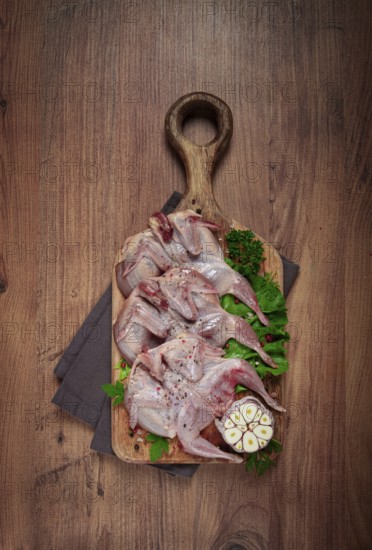 Raw quail meat, on a cutting board, with spices and herbs, top view