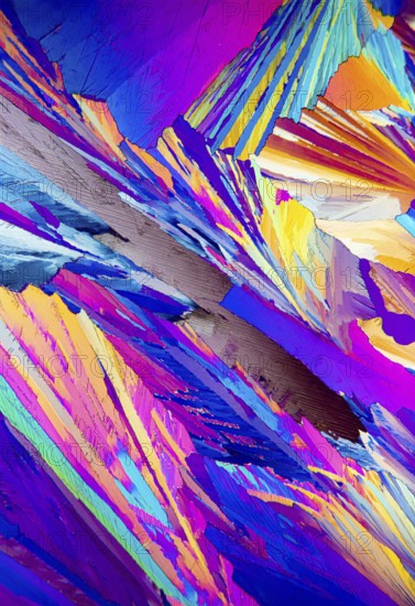 This striking image depicts the colorful patterns of Adipic acid crystals under a microscope, showcasing a vivid array of blues, purples, yellows, and pinks