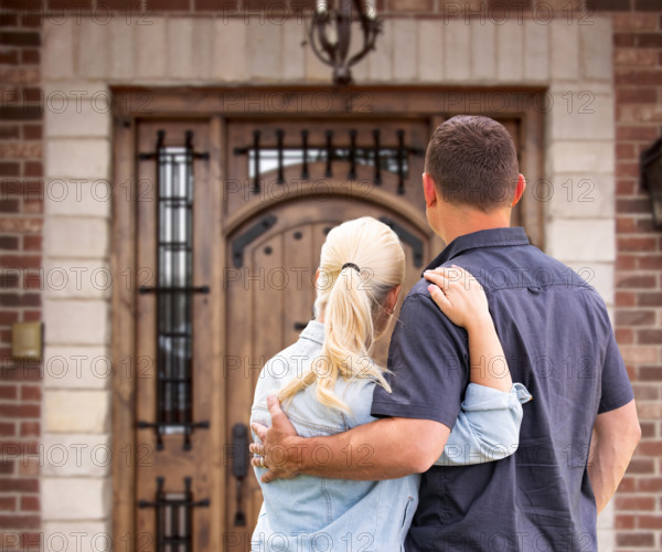 Happy Young Couple Facing Front Door of New House