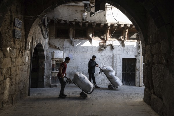 Damascus, Syria. December 4th 2025. Young Syrian men working in the narrow streets near Al Hamediyeh Souk, a busy market in Damascus Old City, Syria