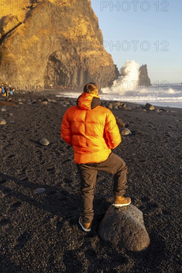 A tourist looking at the beautiful Reynisfjara Black Sand Beach in Iceland in winter