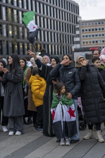 Syrian woman celebrate the end of the Assad regime after the change of power in Syria at a rally on the square in front of the main railway station in Duisburg, North Rhine-Westphalia, Germany