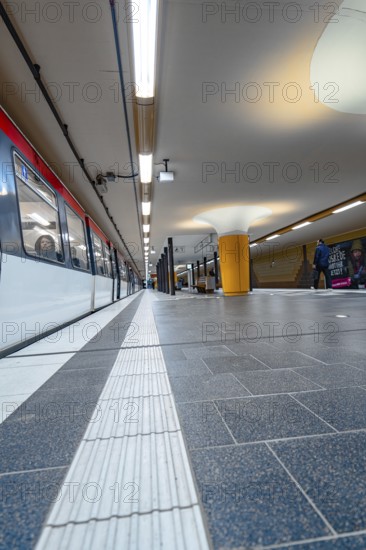 Close-up of an underground railway track with incoming train and bright lighting, Hamburg, Germany