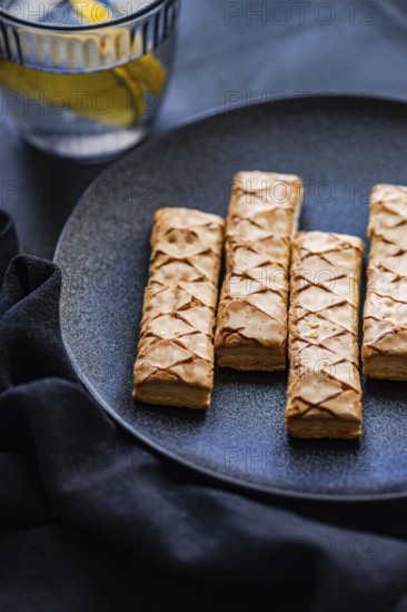 Crisp, golden puff pastry filled with sweet apricot jam, artfully arranged on a sleek black plate. An inviting and tasty treat perfect for a gourmet dessert spread