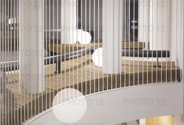 A modern club interior featuring sleek vertical white railings, wooden, and round white lights. The minimalist design offers a clean and sophisticated look
