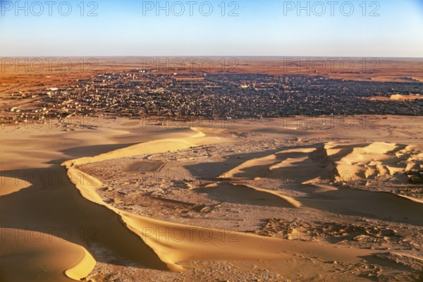 Desert town on the edge of the sand dunes, in the foreground extensive dune landscape, The dunes of the Endless Sahara from the air in Algeria
