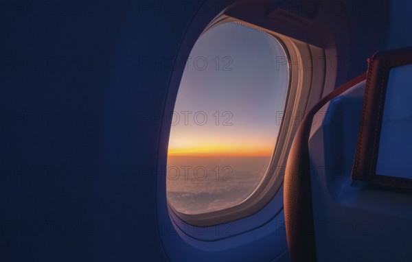 A breathtaking view of a sunrise from an airplane window, capturing the rich orange and blue hues blending over the horizon