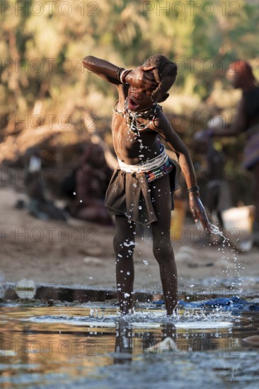 Himba child washing with water on a river, traditional Himba, Kaokoveld, Kunene, Namibia