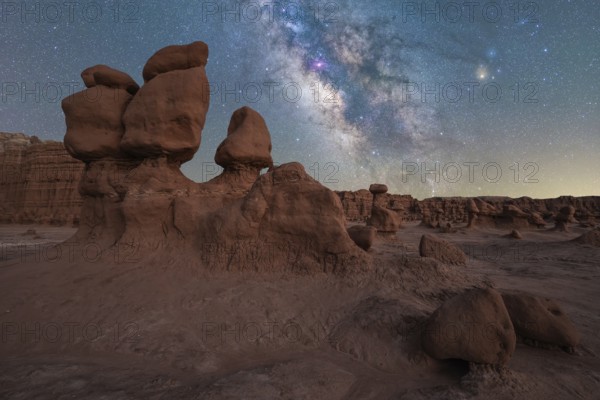 Captivating view of the Milky Way galaxy shining brightly over the unique hoodoo rock formations of Goblin Valley State Park in Utah, presenting a stunning night landscape