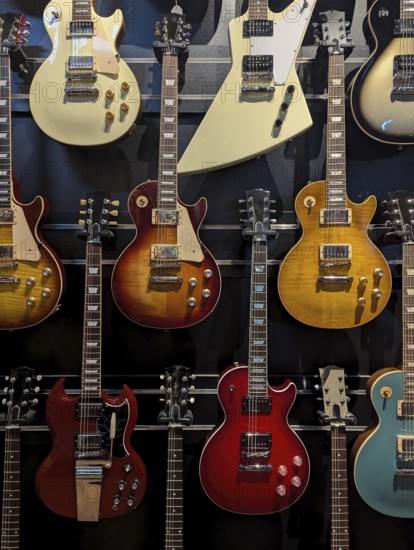 A collection of electric guitars displayed on a wall. Each guitar showcases a unique design and color, highlighting diversity in musical instruments