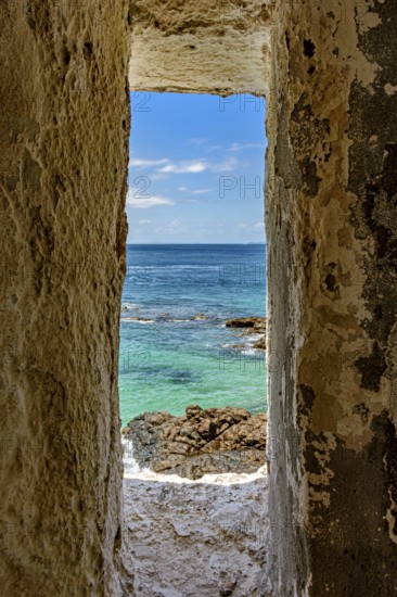 Sea of ??the city of Salvador in Bahia seen through a small window in a sentry box in the historic fort of Farol da Barra, Brazil
