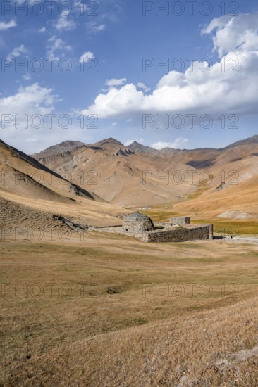 Historic caravanserai Tash Rabat from the 15th century, with yellow hills, Atbashy district in the Naryn region, Kyrgyzstan