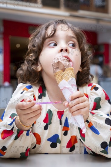 A young girl delights in a chocolate ice cream cone, savoring every bite on a sunny day in a picturesque village, capturing a moment of pure joy and innocence