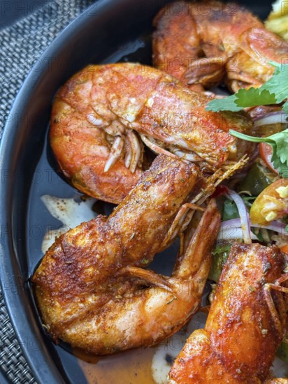 Close up of flavorful dish of seasoned fried shrimp served with a spicy dipping sauce in a Thai cafe setting