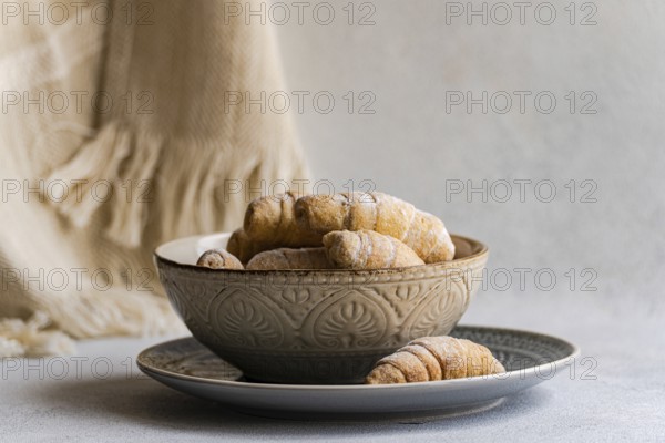 Homemade pastries in a decorative ceramic bowl on a plate. The setup exudes a rustic charm, highlighting the texture and warmth of the freshly baked treats, perfect for cozy settings