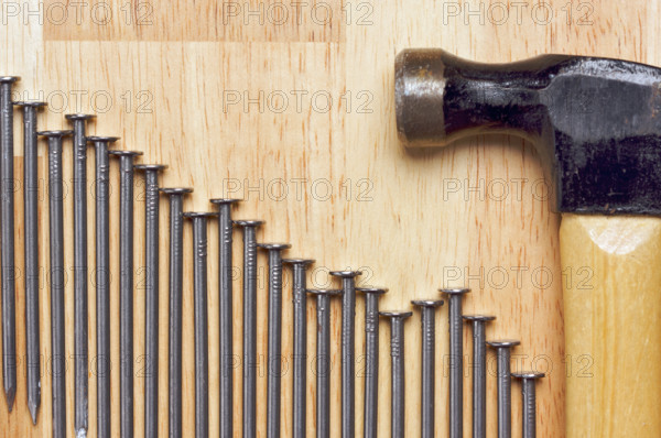 Hammer and Declining Graph of Nails Abstract on Wood Background
