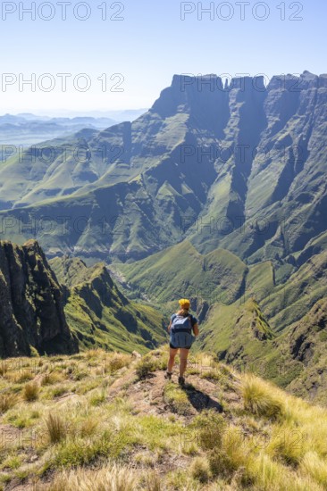 Young hiker looking at the impressive mountains and cliffs of the Drakensberg Mountains, hiking trail on the Sentinel Hiking Trail, Drakensberg, KwaZulu-Natal, South Africa