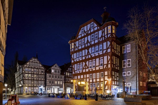 Impressive half-timbered houses in their nocturnal splendour with lights on a quiet square, The historic town hall of Melsungen