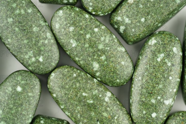 Close-up of green pills scattered on white background