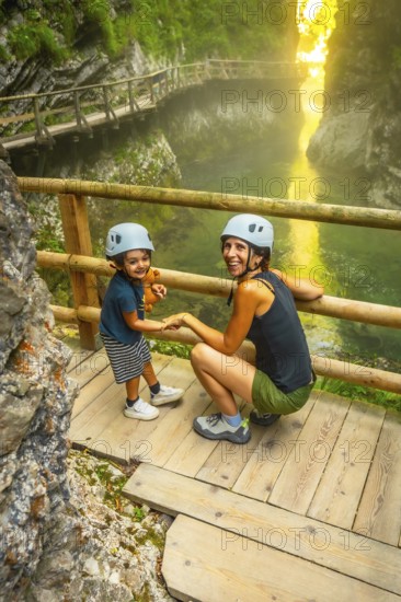 Mother and child wearing helmets, holding hands, enjoying the scenic beauty of vintgar gorge near bled, slovenia