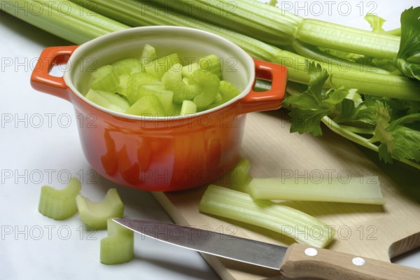 Celery stalks, pieces in pots with kitchen knife