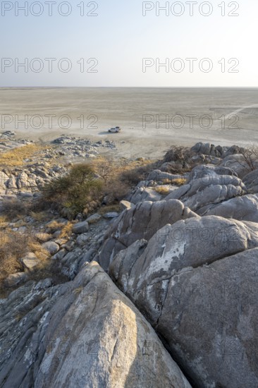 View over round rocks from Kubu Island (Lekubu) to the salt pan with off-road vehicle, at sunrise, Sowa Pan, Makgadikgadi Salt Pans, Botswana