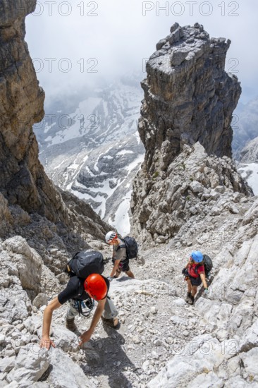 Three hikers climb the Cima falconer mountain peak, Brenta Mountains, Brenta, Brenta-Adamello Natural Park, Trentino, Italy