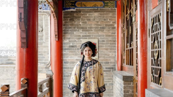 Woman dressed in traditional Qing dynasty clothing stands in Pingyao, China, looking at the camera. The historical setting highlights China's rich cultural heritage