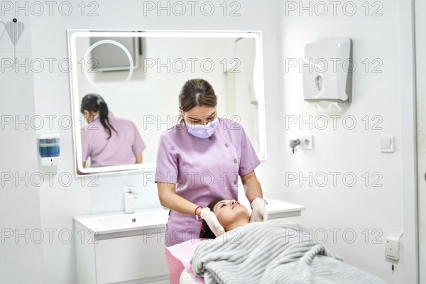 A skilled professional administers a beauty treatment to a client in a clean, modern aesthetic medicine clinic. Soft lighting and calming colors create a soothing atmosphere for relaxation