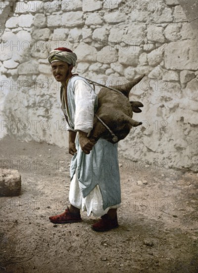 Water carrier, water seller with a goat bellows in Jerusalem, today Israel, Historical, digitally restored reproduction from a 19th century original, Record date not stated