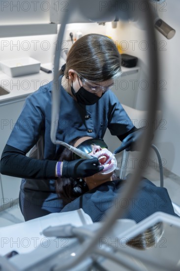Dentist using specialized equipment for teeth whitening treatment on a patient in a modern dental clinic