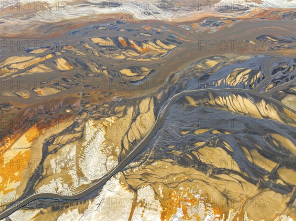 From above, this breathtaking aerial drone image captures the intricate textures and colors of a dry riverbed cutting through a stark, arid environment, showcasing nature's abstract artistry