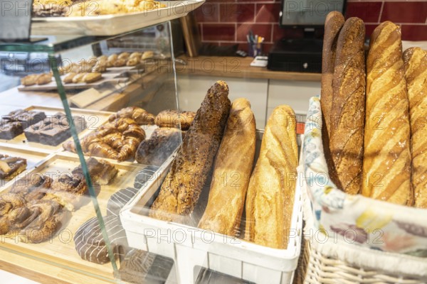 Bakery display case of freshly baked baguettes, croissants and assorted pastries neatly arranged in baskets and trays under glass in a bright, inviting shop setting