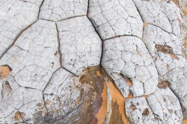 Close-up view of abstract white rocks with deep, intricate cracks and contrasting orange hues. This textured natural background evokes a sense of rugged beauty and geological complexity