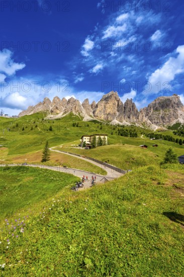 Bikers taking a break at gardena pass admiring the stunning view of the dolomites on a sunny summer day