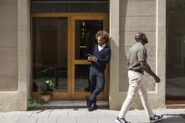 Professionals enjoying a sunny day outside a modern coworking space in Barcelona. The image captures a relaxed work environment that blends city life with productivity