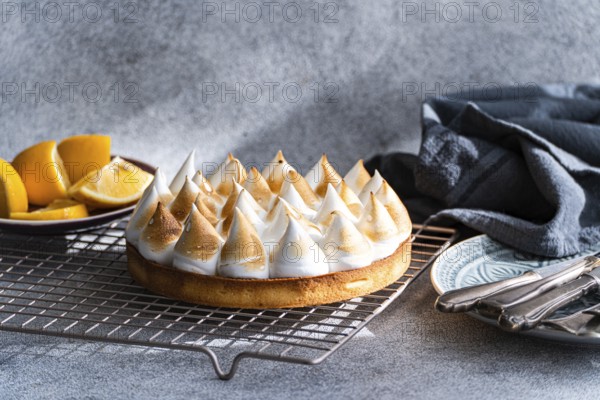 A beautifully homemade lemon cake on a cooling rack, accompanied by fresh lemon slices and vintage utensils. The scene offers a cozy