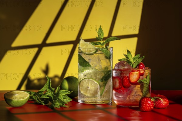 Glasses of classic mojito with lime and mint, and strawberry mojito featuring fresh strawberries, set on a red surface with a warm yellow background, sunlight casting shadows