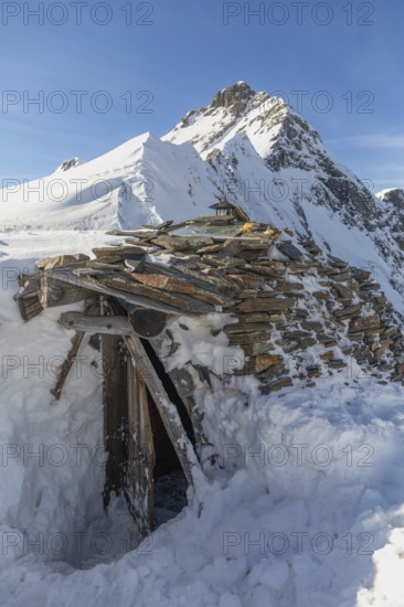 A rustic stone hut surrounded by snow against a majestic alpine backdrop. Ideal for ski touring enthusiasts seeking solitude and adventure in the wintry mountains