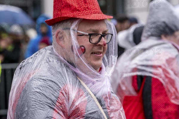 Rose Monday procession in Düsseldorf, parade participants, foot groups, make themselves rainproof, at street carnival, sometimes heavy rain, North Rhine-Westphalia, Germany