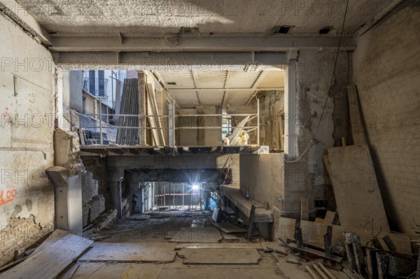 A construction site depicting an interior under renovation. Exposed beams, scaffolding, and building materials highlight the transformation process in progress