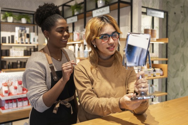 A friendly cosmetics store worker assists a customer trying on products. The customer holds a mirror, reflecting a vibrant store ambiance focused on personalized beauty service