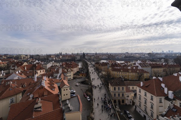Beautiful aerial snapshot of Prague showcasing a crowded street flanked by traditional terracotta rooftops, with the city's historic architecture extending into the horizon under a dramatic cloudy sky