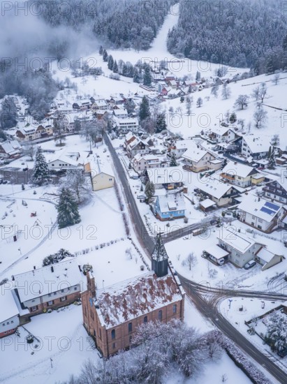 Snowy town view with church, surrounded by wooded hills, Enzklösterle, district of Calw, Black Forest, Germany