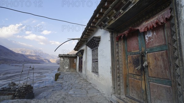 Traditional colorful wooden doors and stone walls with mountain views at dusk, trekking at Annapurna Circuit, Nepal